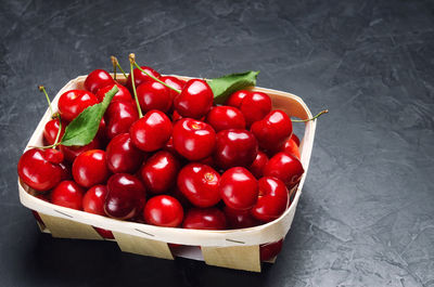 Fresh ripe red cherry in a basket on a gray concrete background, summer berry, space for text