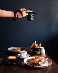 Cropped hand photographing food with camera on table