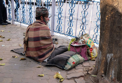 Man sitting by fence in city