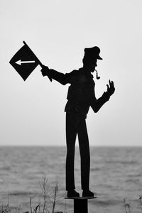 Silhouette man standing by sea against clear sky