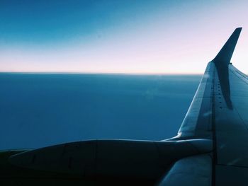 Close-up of airplane flying over sea against clear blue sky