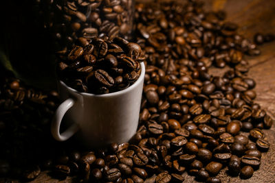 Roasted coffee beans in cup on table