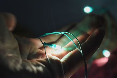 Cropped hand holding illuminated lighting equipment in darkroom