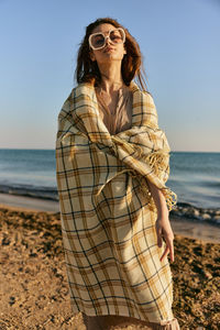 Young woman standing at beach against sky