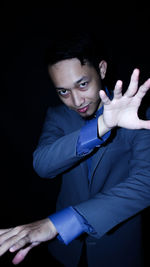 Portrait of young man standing against black background