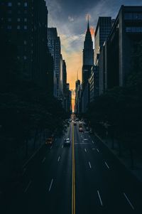Road amidst buildings in city during sunset
