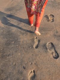 Low section of woman walking on sand at beach