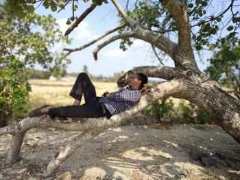 Man sitting on tree trunk against plants