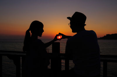 Silhouette couple against sea during sunset