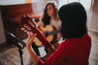 Friends practicing while playing guitar at home