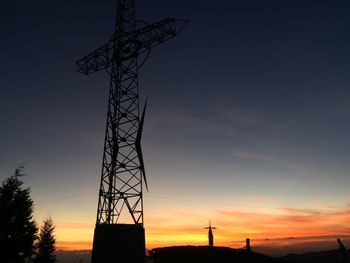 Low angle view of silhouette electricity pylon against sky during sunset