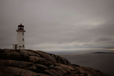 Lighthouse by sea against sky