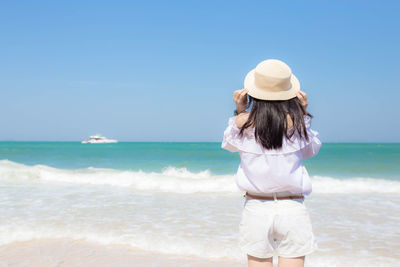 Rear view of woman on beach against clear sky