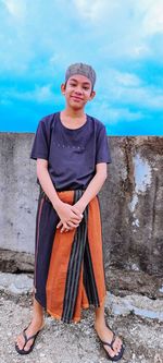 Portrait of smiling boy standing against sky