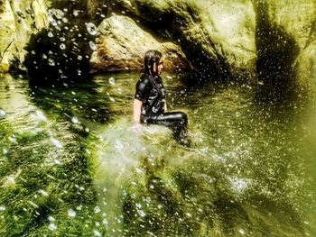 Side view of wet woman sitting in river