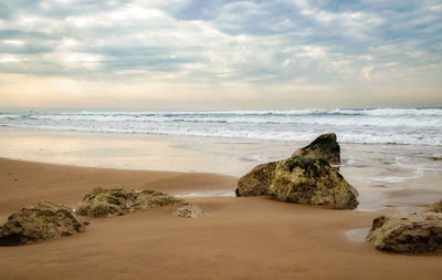 Scenic view of rocks on beach against sky