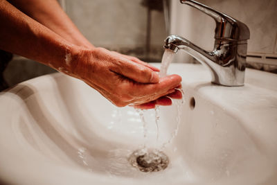 Cropped image of man washing hands in sink