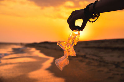 Low section of man holding heart shape on beach