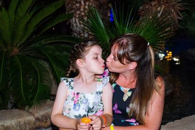 Mother and daughter kissing outdoors at night