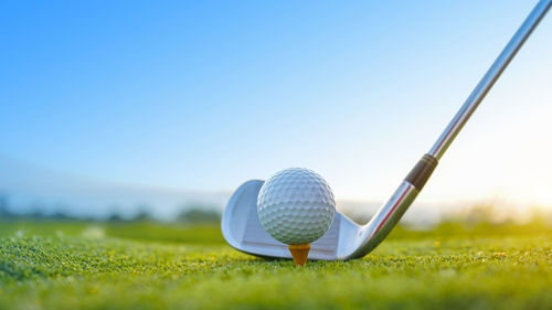 Golf clubs and golf balls on a green lawn in a beautiful golf course with morning sunshine. 