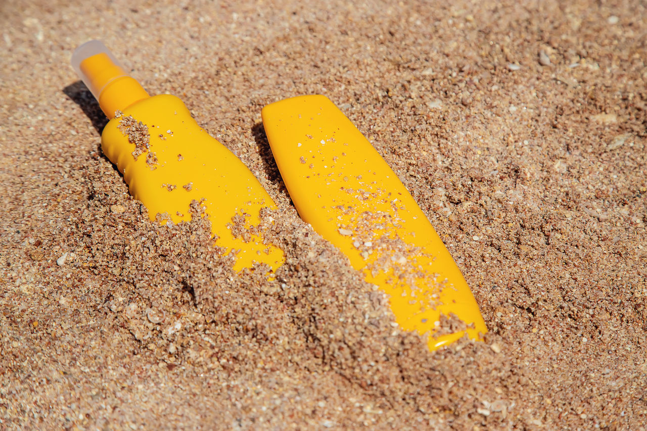 HIGH ANGLE VIEW OF YELLOW AND TEXT ON SAND