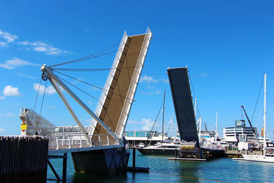 Sailboats moored at harbor against blue sky