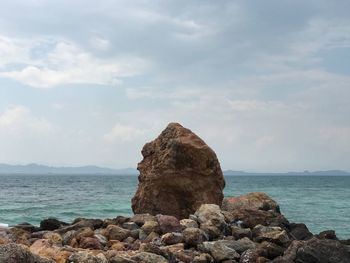 Rock formation by sea against sky