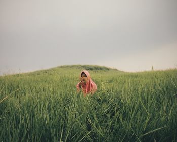 Woman in religious dress amidst grass at mountain against sky