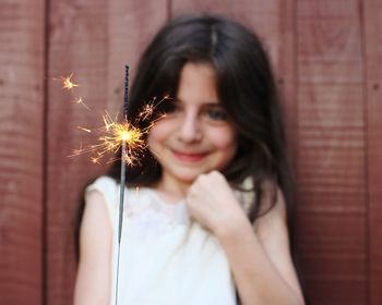 Close-up of smiling girl holding lit sparkler