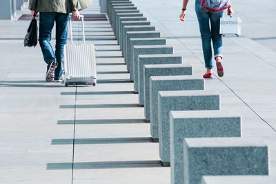 Low section of people carrying luggage while walking on street