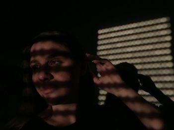 Young woman looking away against black background