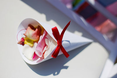 The rose petals in the wedding envelope with a red ribbon lying on the chair