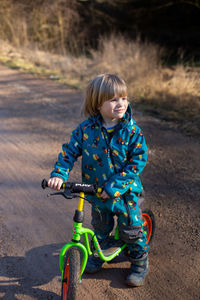 Portrait of boy playing with push scooter on field