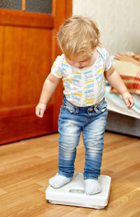 Girl standing on weight scale at home