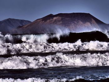 Scenic view of sea and mountains against clear sky