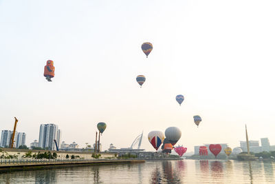 Hot air balloons flying in city against clear sky