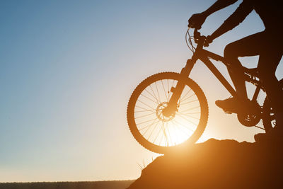 Silhouette man riding bicycle against sky during sunset