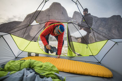 Two men set up sleeping pads in their tent during climbing trip.