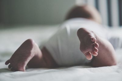 Low section of baby boy relaxing on bed