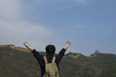 Rear view of man with arm raised standing at great wall of china