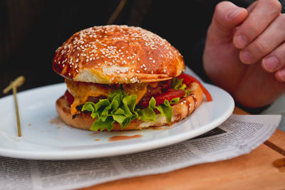 Cropped image of person eating burger at restaurant