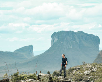 Rear view of man walking on mountain against sky