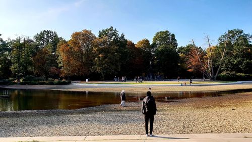 Rear view of man by lake against sky