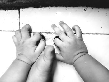 Cropped hands of baby by parent foot