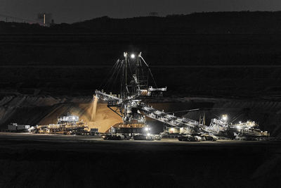 Illuminated factory against sky at night