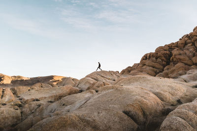 Low angle view of man walking on rocky mountain against sky