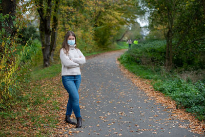 Woman standing on road amidst trees during autumn