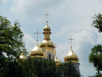 Low angle view of church amidst trees and buildings against sky
