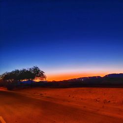 Scenic view of field against clear blue sky during sunset