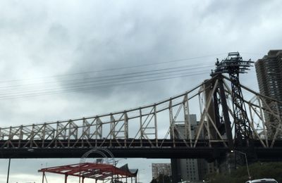 Low angle view of electricity pylon against cloudy sky